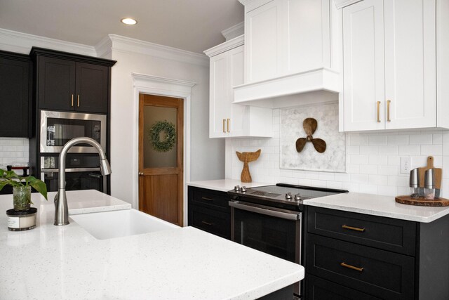 kitchen with white cabinetry, crown molding, dark cabinets, and stainless steel appliances