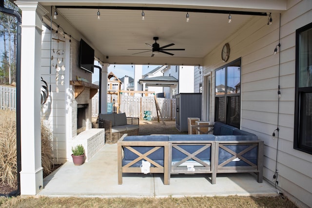 view of patio / terrace with a ceiling fan, an outdoor living space with a fireplace, and fence