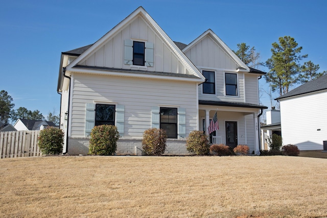 modern inspired farmhouse with covered porch, board and batten siding, a front yard, and fence