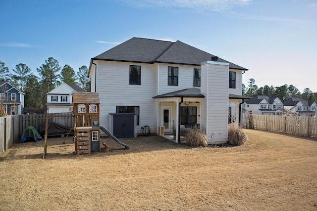 rear view of house with a shingled roof, a playground, a yard, a fenced backyard, and a patio area