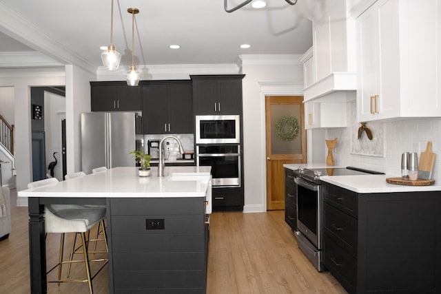 kitchen with dark cabinetry, wall chimney exhaust hood, light countertops, and stainless steel appliances