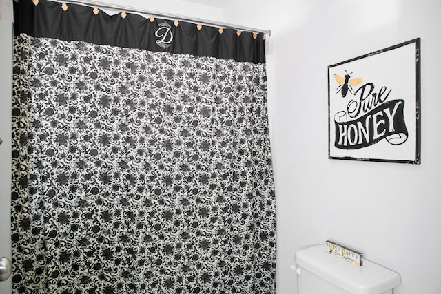 bathroom with a shower with curtain and toilet