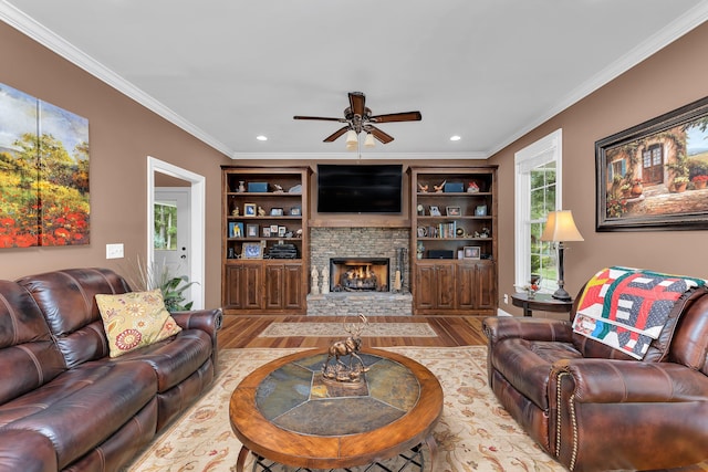 living room featuring a fireplace, light hardwood / wood-style flooring, ceiling fan, and crown molding