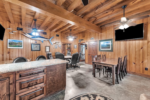 dining area featuring beamed ceiling, wood walls, and concrete floors