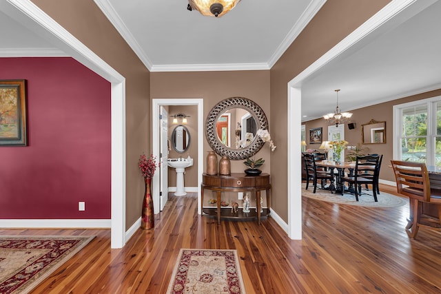 foyer with an inviting chandelier, dark hardwood / wood-style floors, and ornamental molding