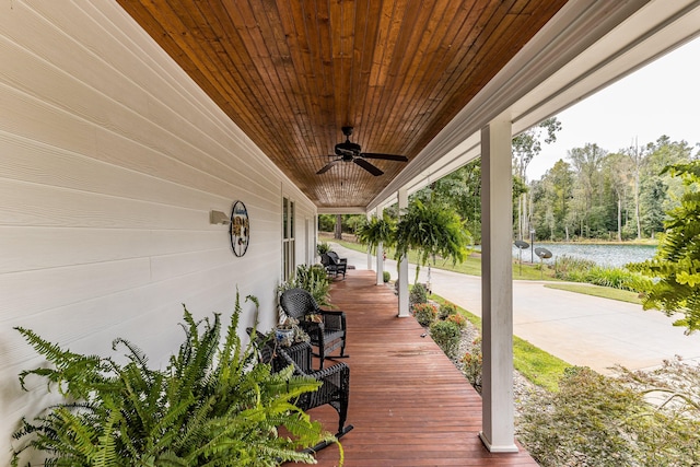 wooden deck with ceiling fan, a porch, and a water view