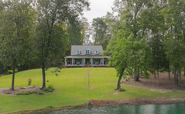 farmhouse-style home with covered porch, a water view, and a front yard