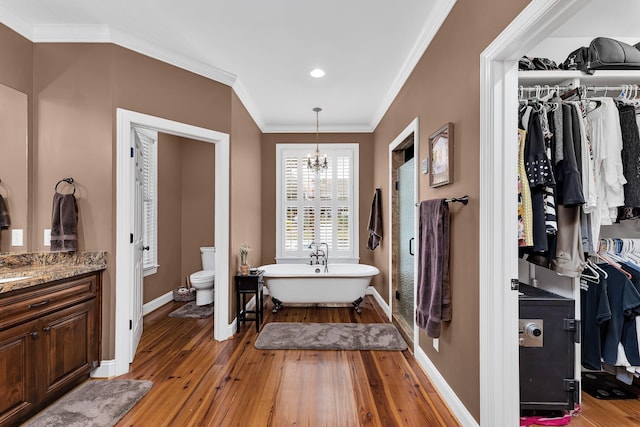 bathroom with a bathing tub, crown molding, vanity, and wood-type flooring