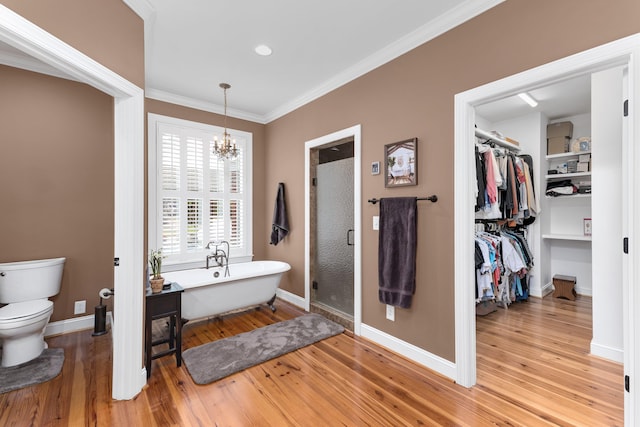 bathroom with ornamental molding, separate shower and tub, wood-type flooring, an inviting chandelier, and toilet