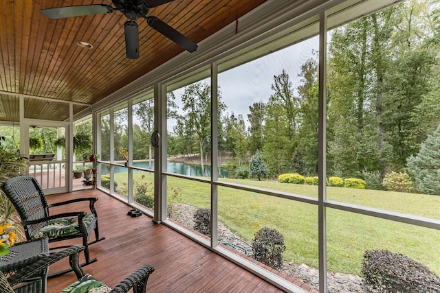 unfurnished sunroom with ceiling fan, a water view, and wood ceiling