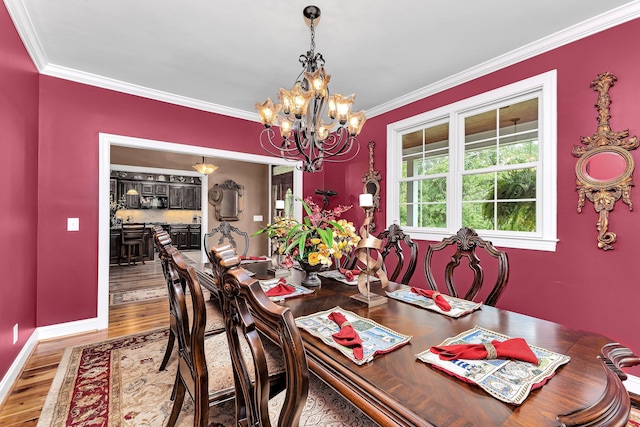 dining area with crown molding, hardwood / wood-style floors, and an inviting chandelier