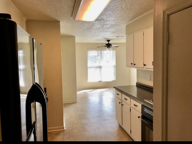 2609 Claymont Rd, Hephzibah, GA 30815 - kitchen with oven, a textured ceiling, dark countertops, freestanding refrigerator, and white cabinets