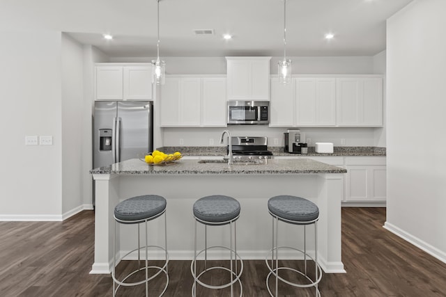 kitchen featuring white cabinets, hanging light fixtures, a center island with sink, and appliances with stainless steel finishes