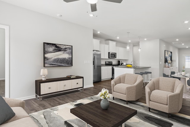 living room with sink, ceiling fan, and dark hardwood / wood-style flooring