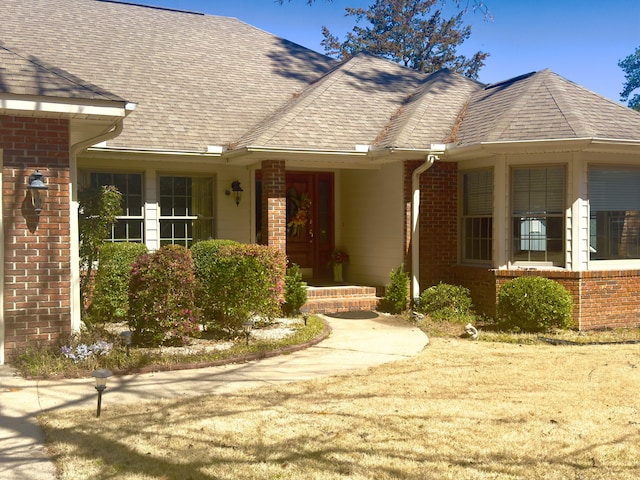 ranch-style home featuring brick siding and roof with shingles