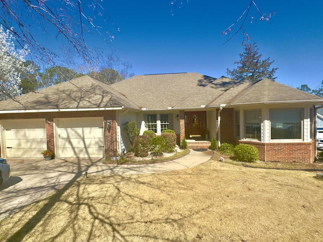 ranch-style home with brick siding, an attached garage, concrete driveway, and roof with shingles