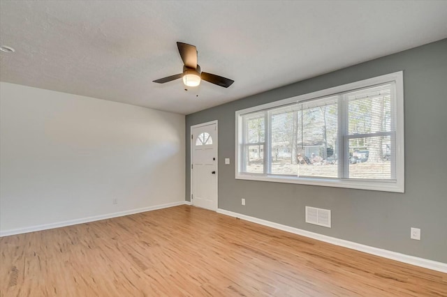 interior space featuring light wood finished floors, baseboards, visible vents, and ceiling fan