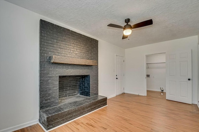 unfurnished living room with ceiling fan, a fireplace, baseboards, and wood finished floors