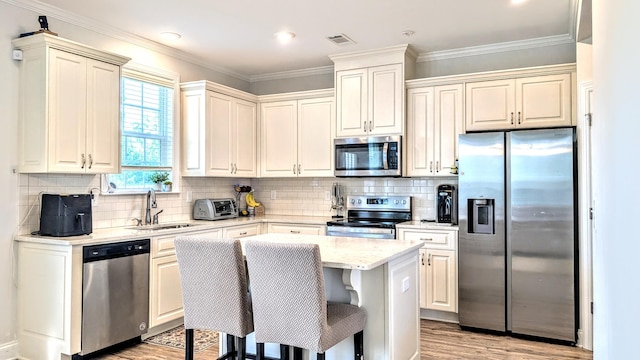 3113 Lobella Dr, Grovetown, GA 30813 - kitchen featuring appliances with stainless steel finishes, light wood-style flooring, a center island, light stone counters, and tasteful backsplash