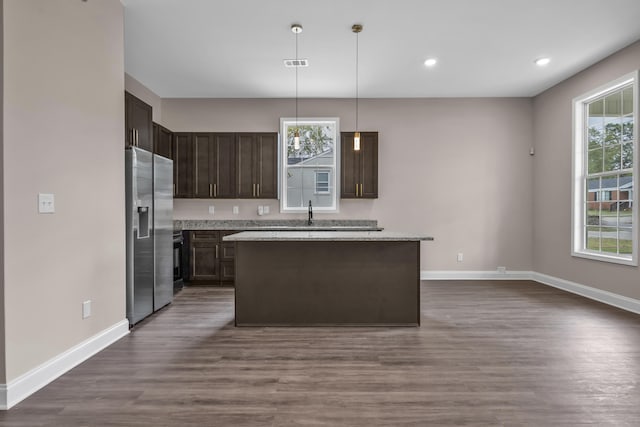 kitchen with hanging light fixtures, dark hardwood / wood-style flooring, stainless steel refrigerator with ice dispenser, dark brown cabinets, and a kitchen island