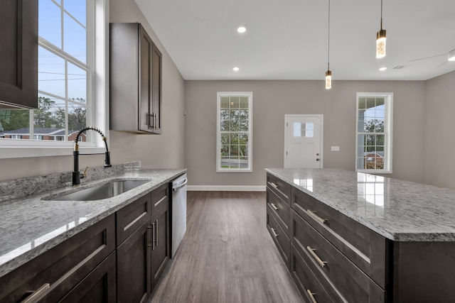 kitchen featuring light stone countertops, a wealth of natural light, sink, light hardwood / wood-style flooring, and dishwasher