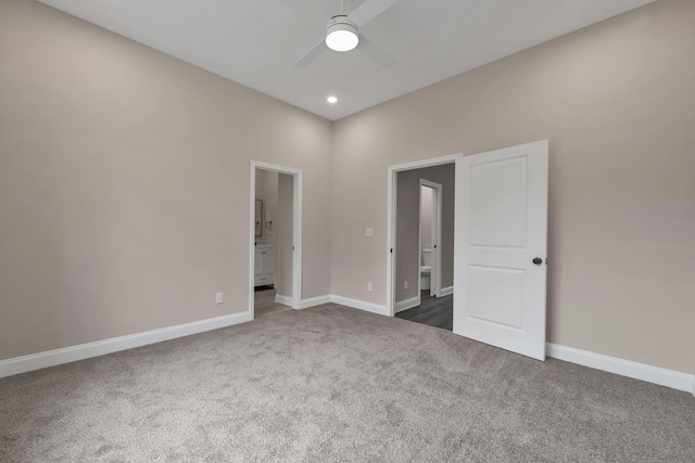 unfurnished bedroom with dark colored carpet, ceiling fan, and ensuite bath