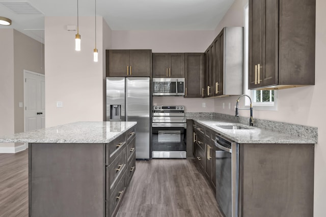 kitchen featuring light stone countertops, sink, dark wood-type flooring, pendant lighting, and appliances with stainless steel finishes