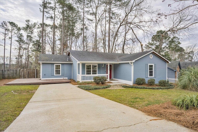 ranch-style house with a front yard, covered porch, fence, and concrete driveway