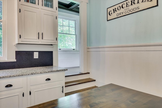413 S Liberty St, Waynesboro, GA 30830 - kitchen with white cabinetry, glass insert cabinets, a wainscoted wall, and decorative backsplash