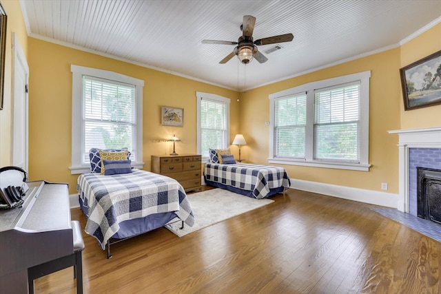 413 S Liberty St, Waynesboro, GA 30830 - bedroom with multiple windows, wood finished floors, ornamental molding, a fireplace with flush hearth, and baseboards