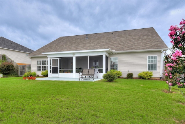 back of property with a sunroom, a patio, and a lawn