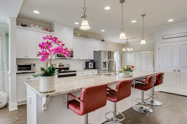 kitchen with a large island, hanging light fixtures, white cabinets, and stainless steel appliances