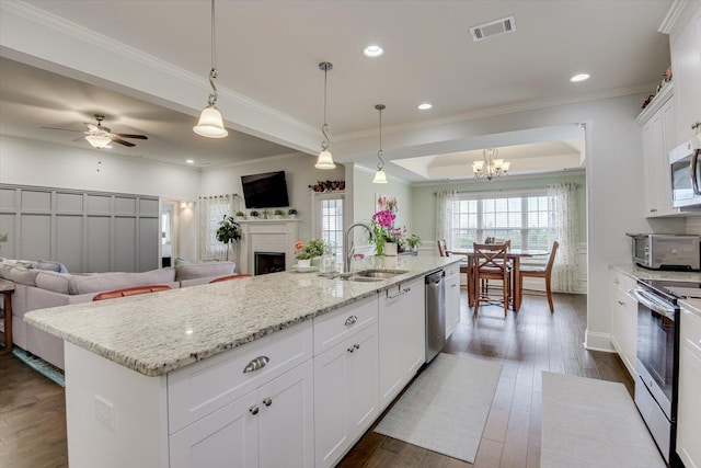 kitchen with sink, an island with sink, white cabinets, ceiling fan with notable chandelier, and appliances with stainless steel finishes