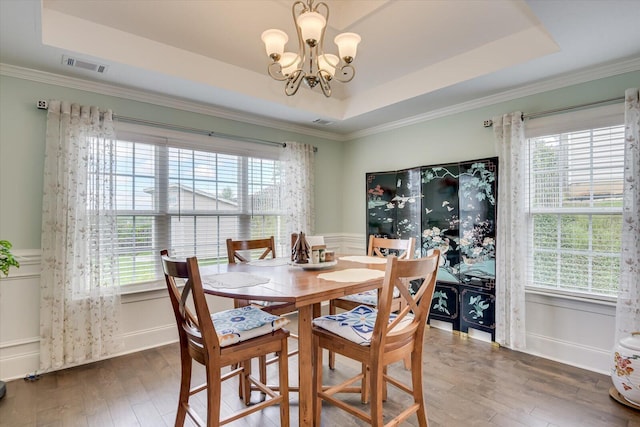 dining room with a raised ceiling, dark hardwood / wood-style flooring, and an inviting chandelier