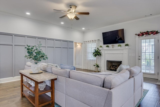 living room with hardwood / wood-style flooring, a brick fireplace, ceiling fan, and ornamental molding