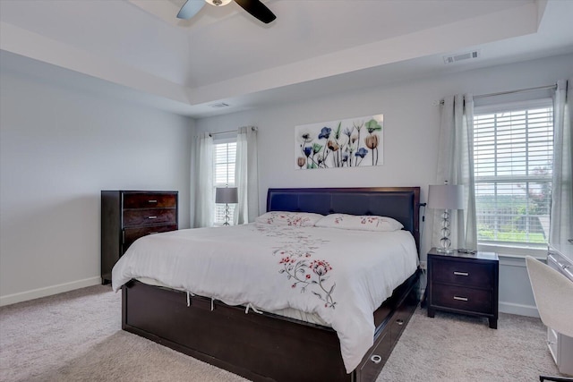 carpeted bedroom featuring a raised ceiling and ceiling fan