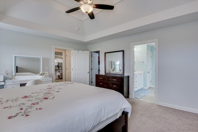 carpeted bedroom featuring a raised ceiling, connected bathroom, and ceiling fan