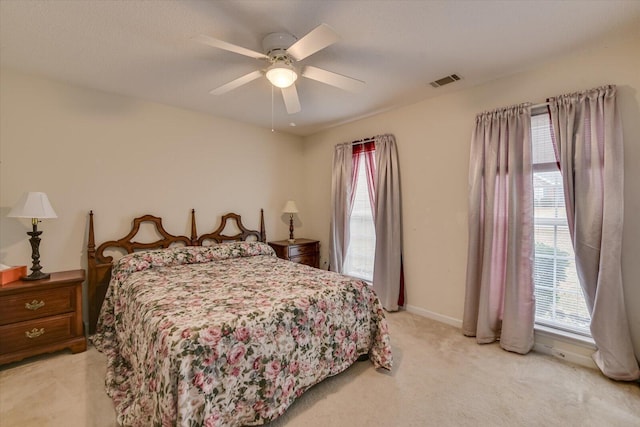 bedroom with baseboards, visible vents, a ceiling fan, and light colored carpet
