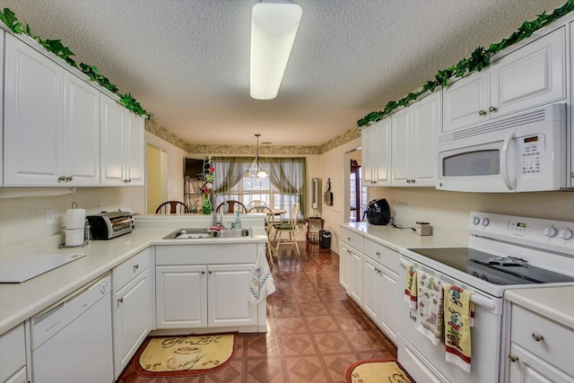 kitchen featuring a sink, white appliances, a peninsula, a textured ceiling, and white cabinetry