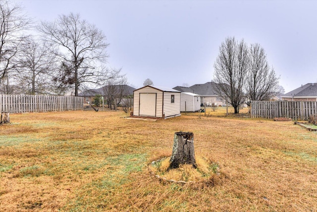 view of yard with a fenced backyard, an outdoor structure, and a storage shed