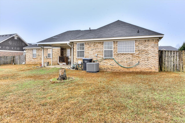 rear view of property featuring a fenced backyard, central AC unit, brick siding, and a lawn