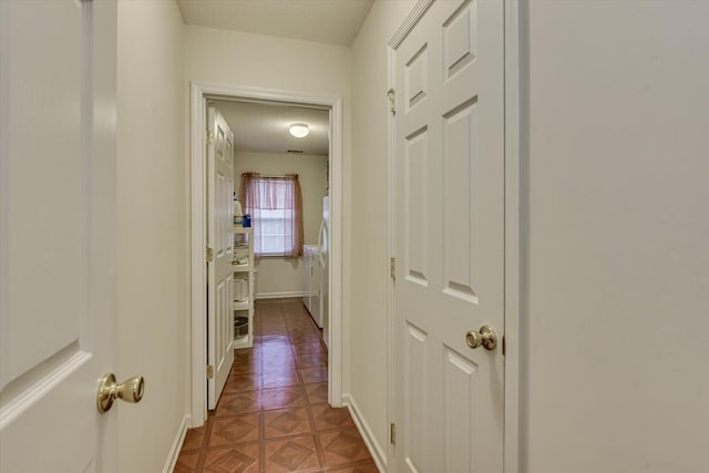hallway featuring baseboards, tile patterned floors, and a textured ceiling