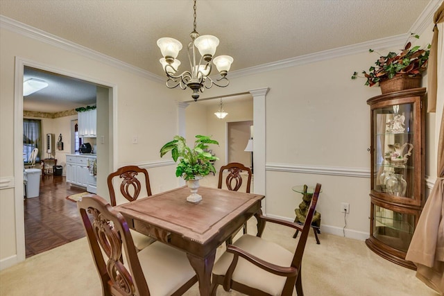 dining space with an inviting chandelier, ornamental molding, and a textured ceiling