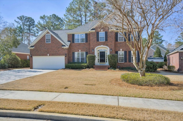 colonial home featuring a garage, driveway, brick siding, and a front lawn