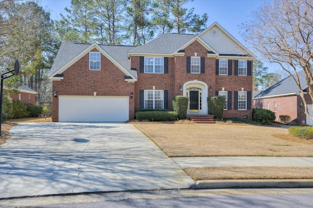 colonial home with a garage, concrete driveway, brick siding, and roof with shingles