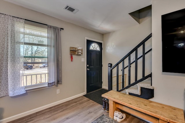 foyer featuring a healthy amount of sunlight, stairs, visible vents, and wood finished floors