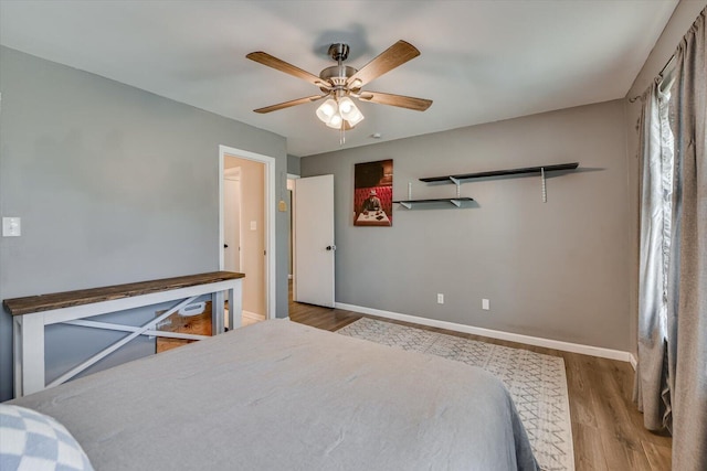 bedroom with ceiling fan, baseboards, and wood finished floors