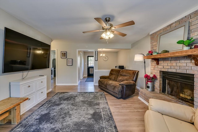 living room with a ceiling fan, a fireplace, baseboards, and wood finished floors