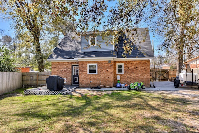 rear view of property with a fenced backyard, a lawn, and brick siding