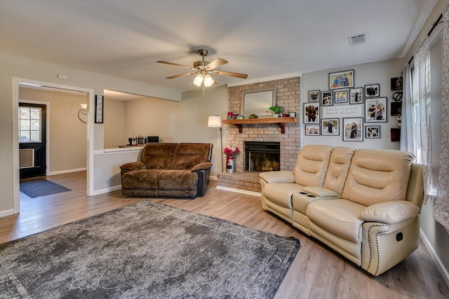 living area featuring visible vents, a fireplace, baseboards, and wood finished floors